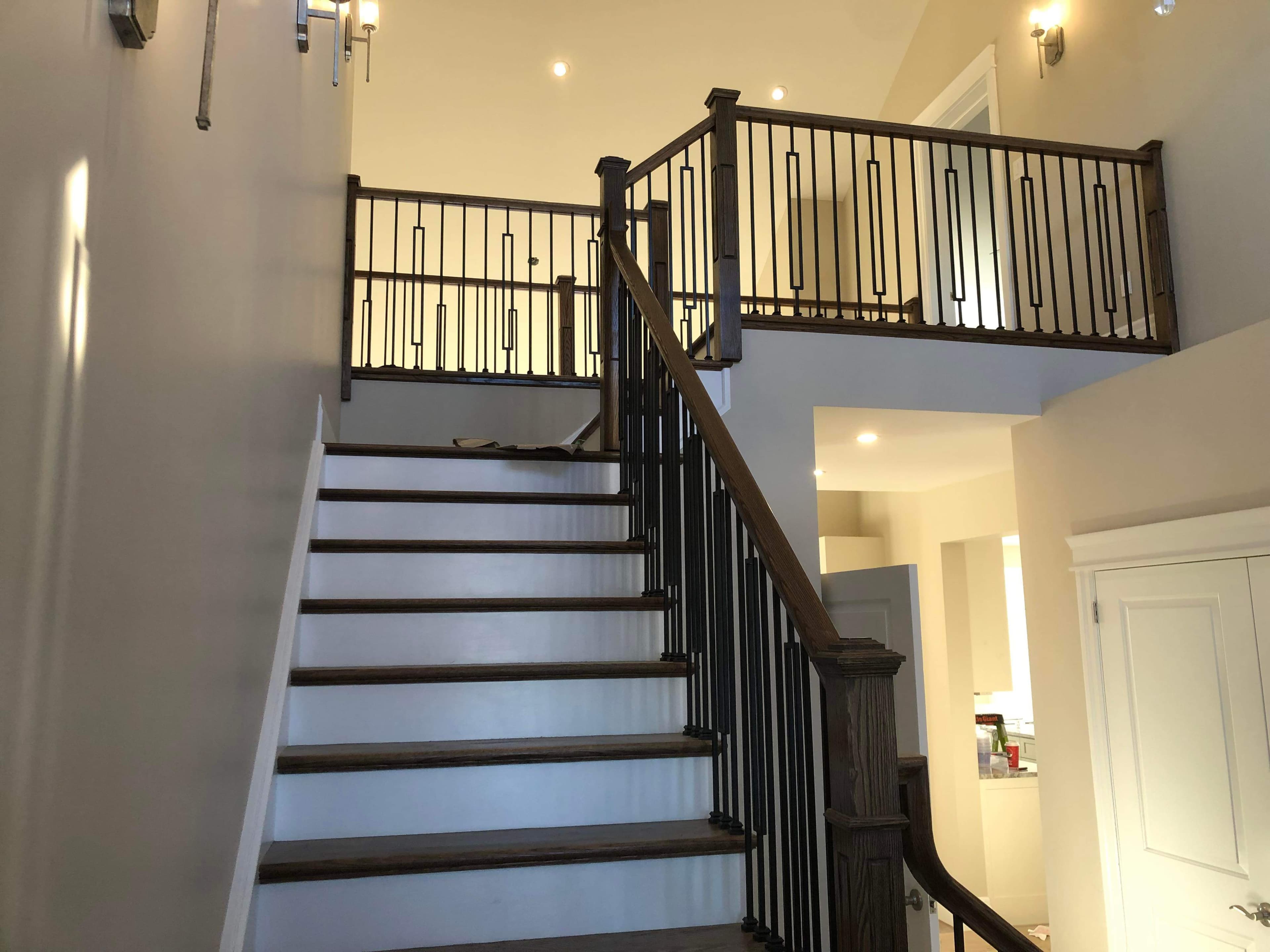 Finished interior staircase with dark stained treads, wood posts, and black balusters.