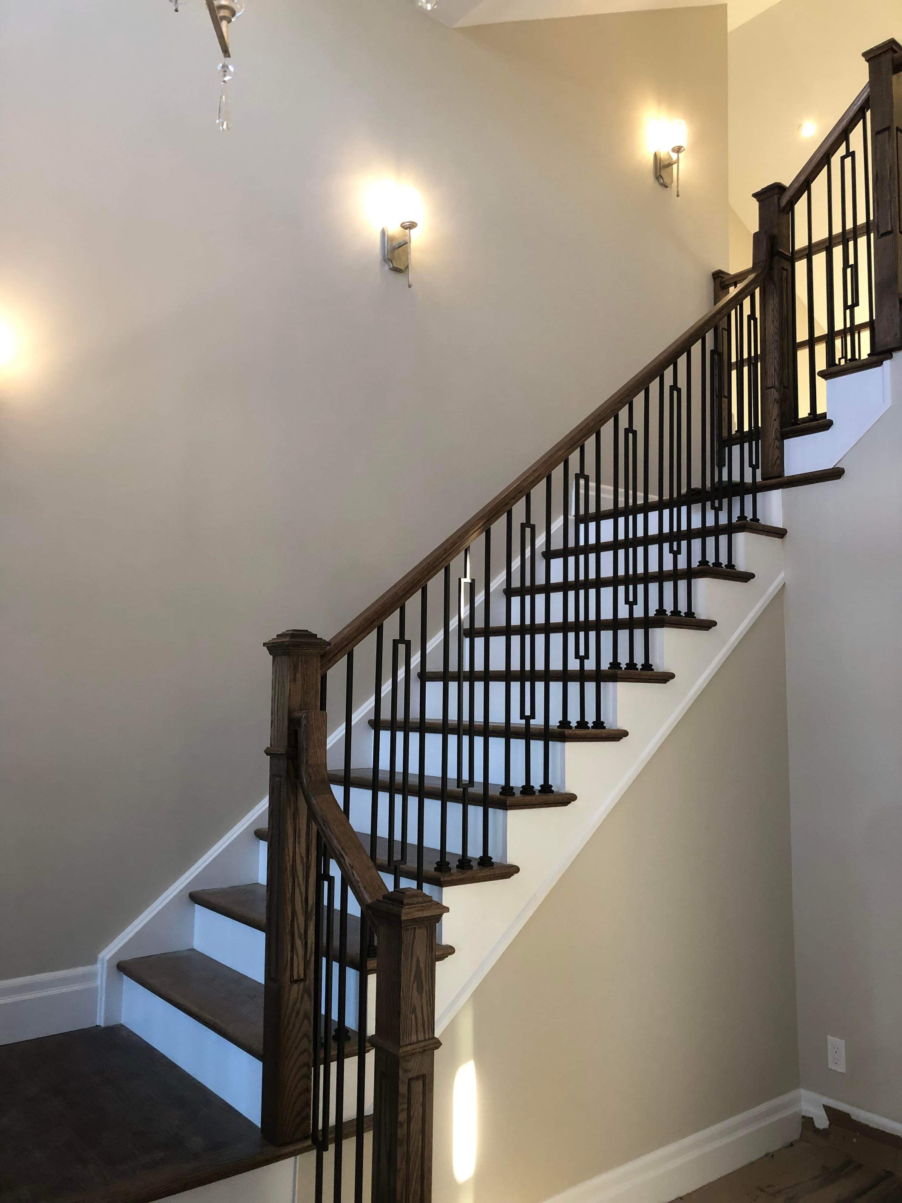 Tall entry staircase with stained wood railings and black metal balusters.