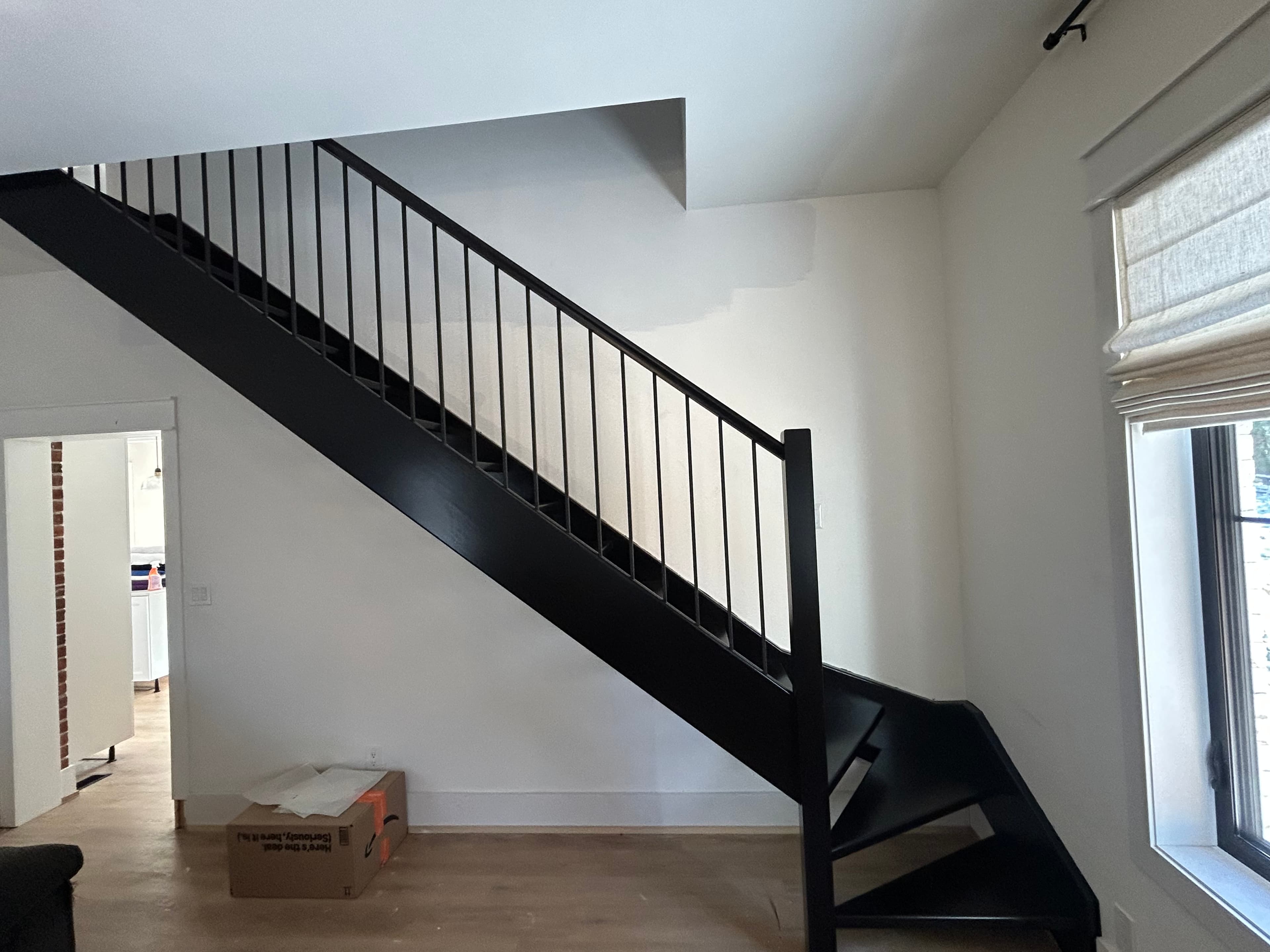 Black side staircase with matching black railing in a white room.