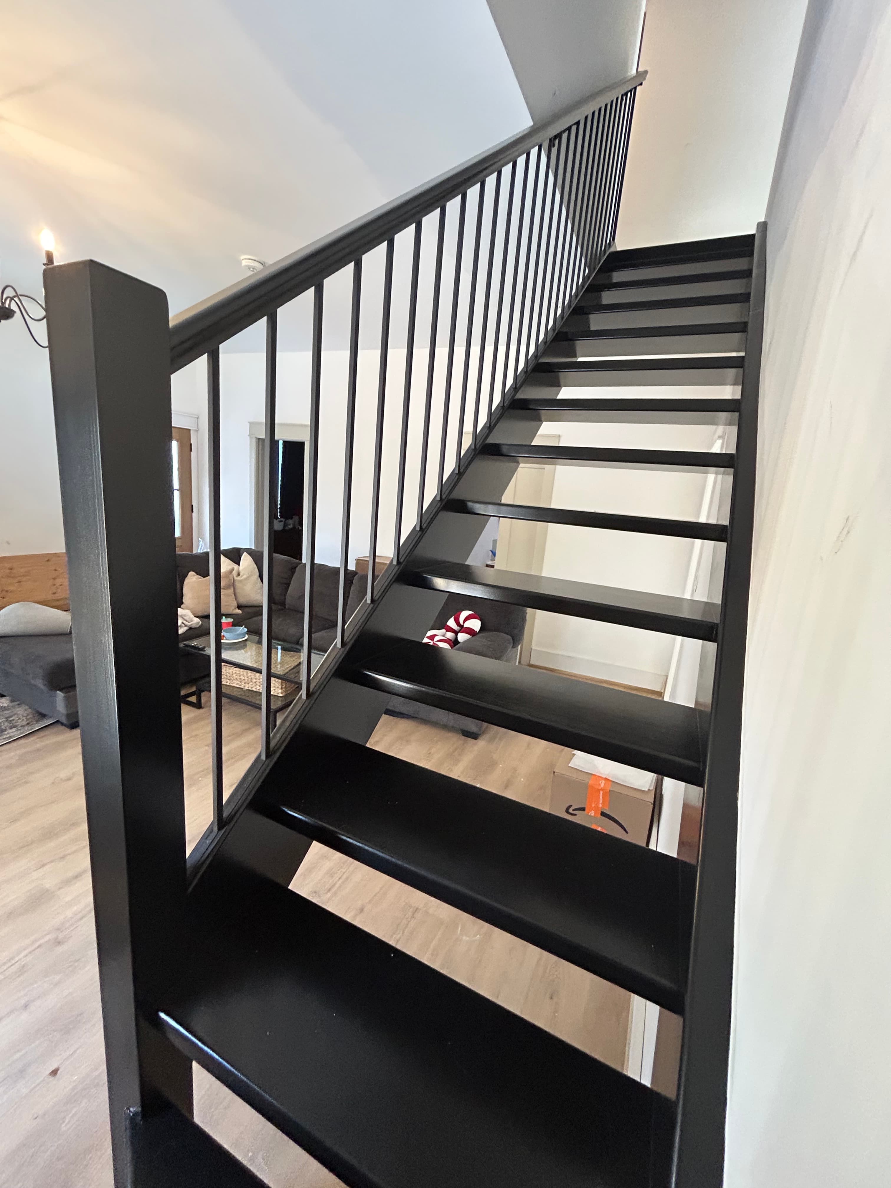 Close view of black open-riser stair treads and vertical rail balusters.
