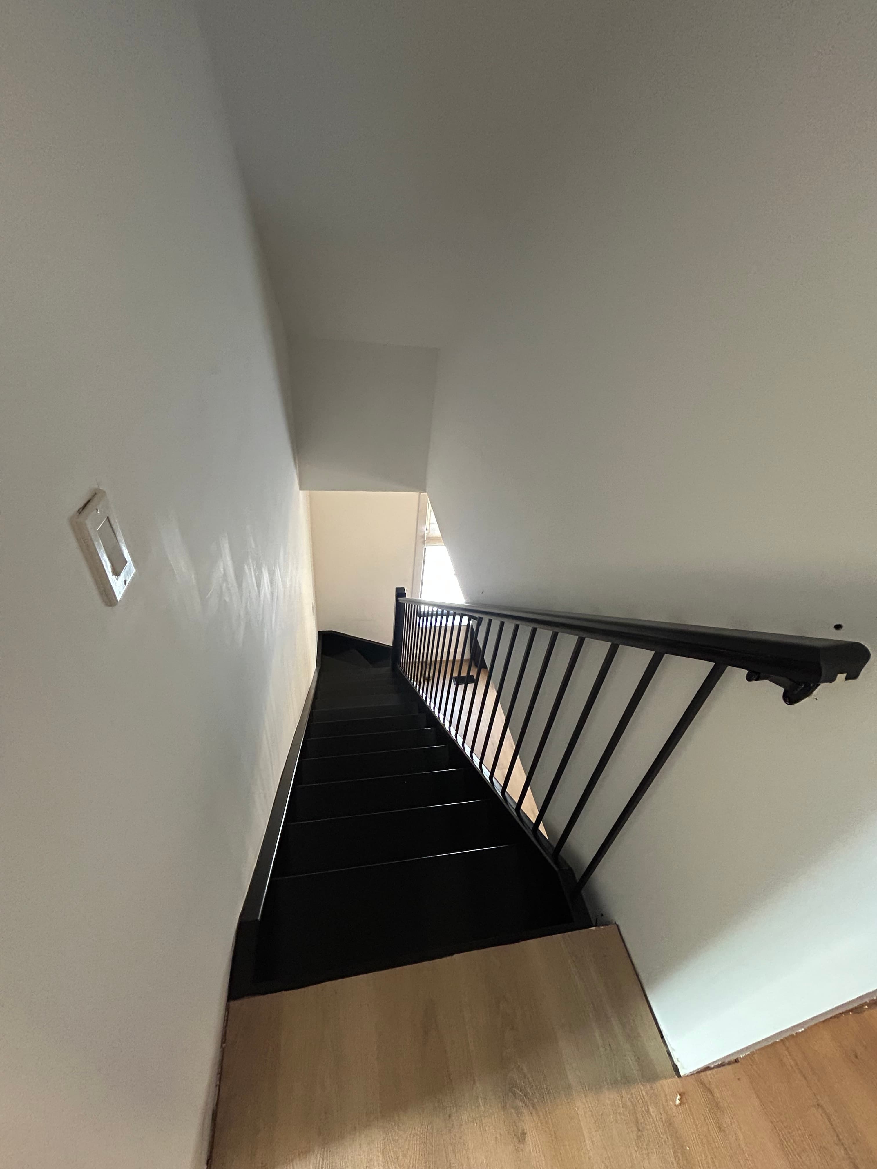 Compact stairwell with dark steps and black railing.