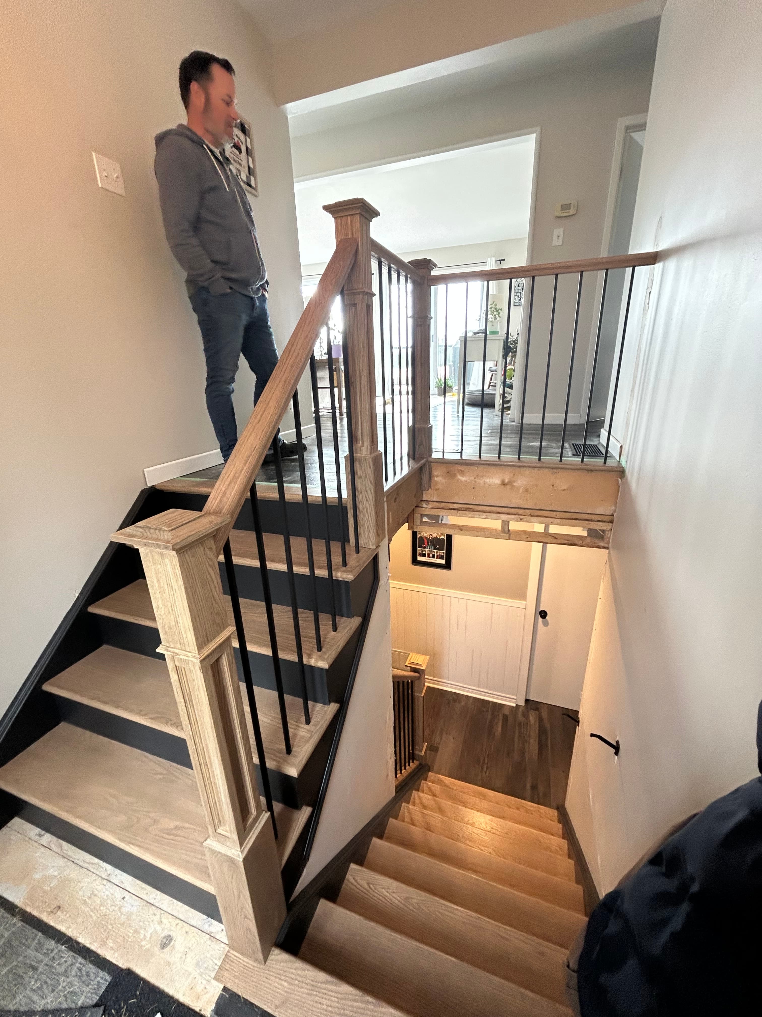 Upper landing guardrail with wood posts and black balusters.