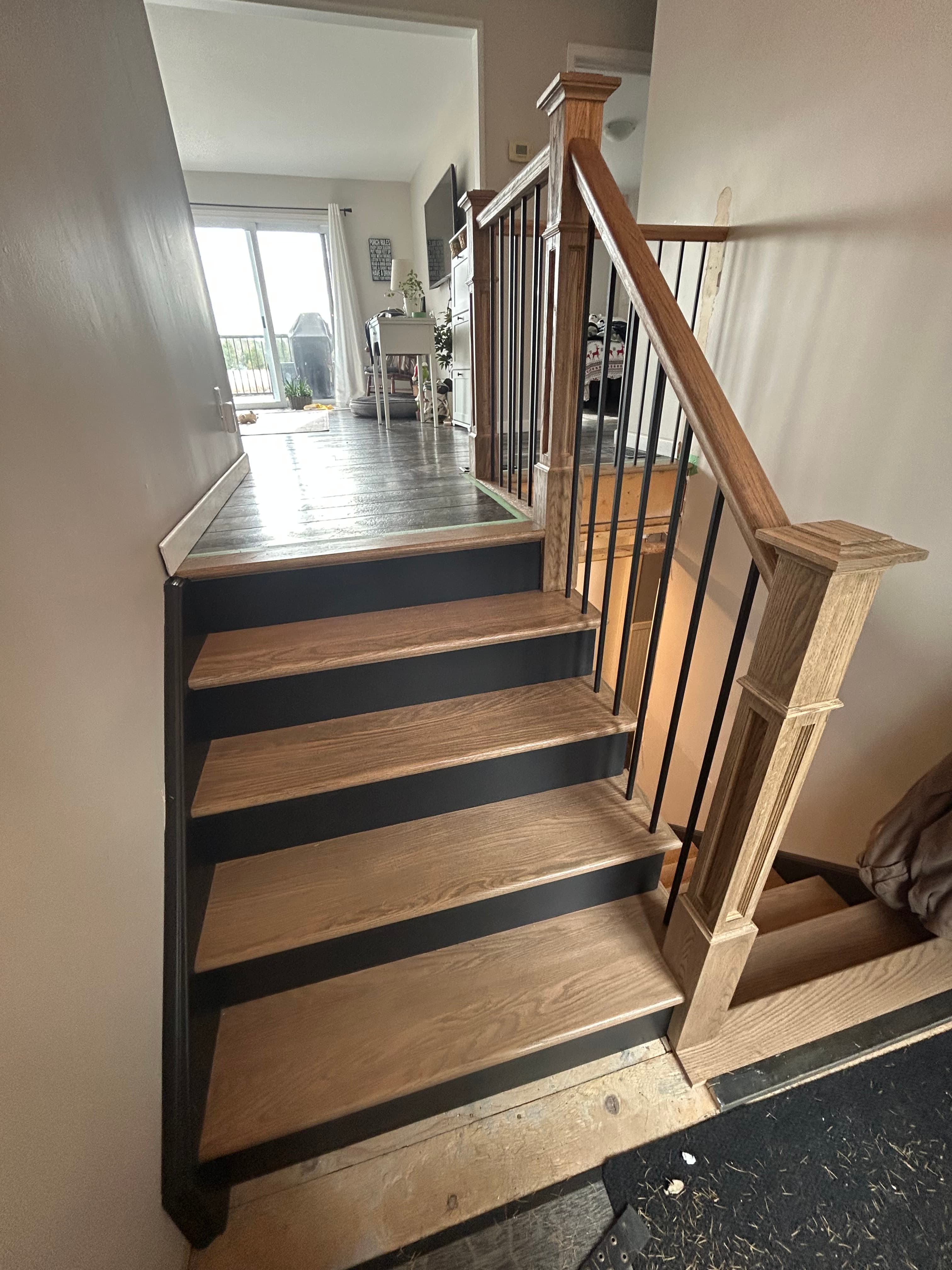 Two-tone staircase with natural wood treads, black risers, and black balusters.