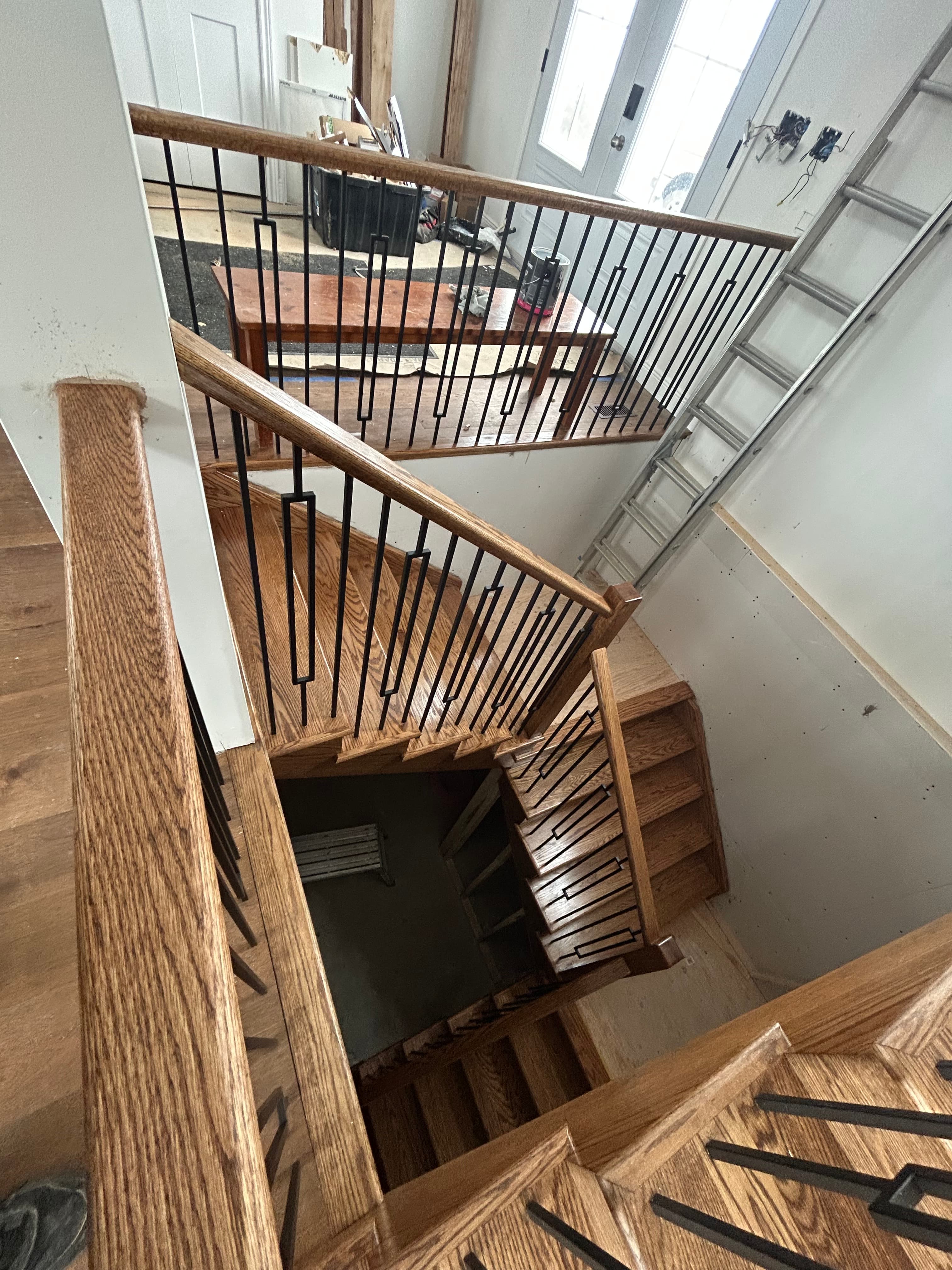 Top-down view of stained wood railings and black balusters around a stair opening.