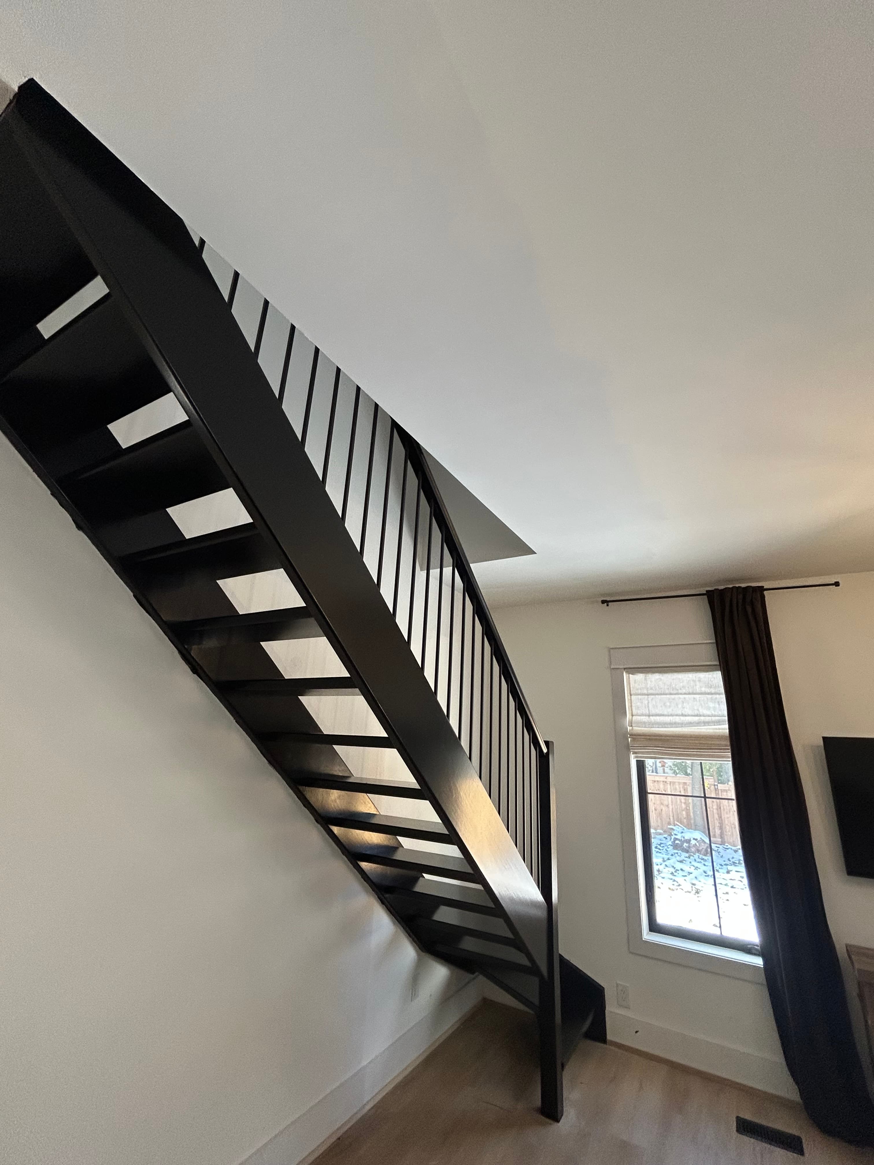 Steep black open-riser staircase with integrated black railing.