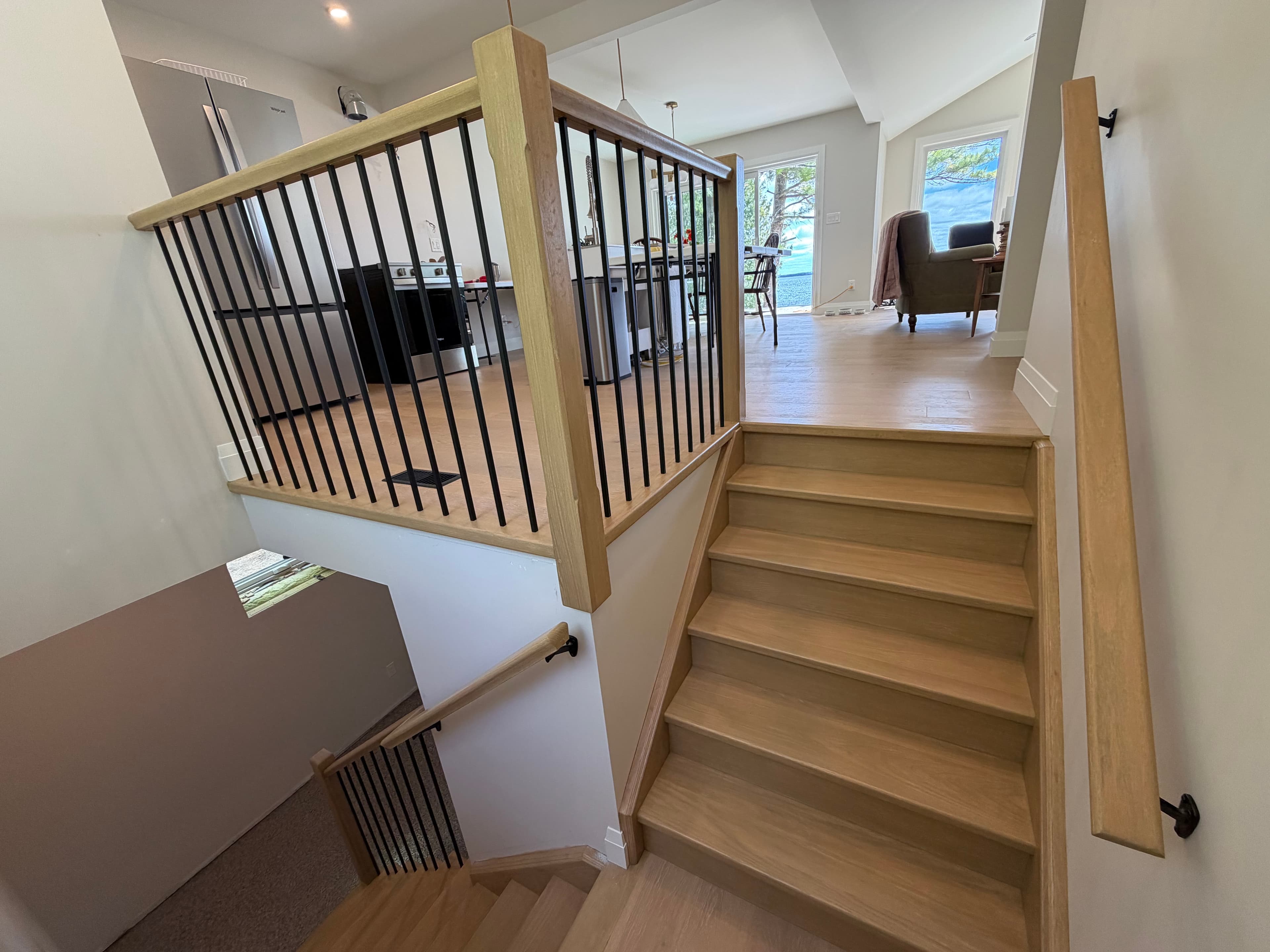 Oak-toned stair and guardrail with black metal balusters.